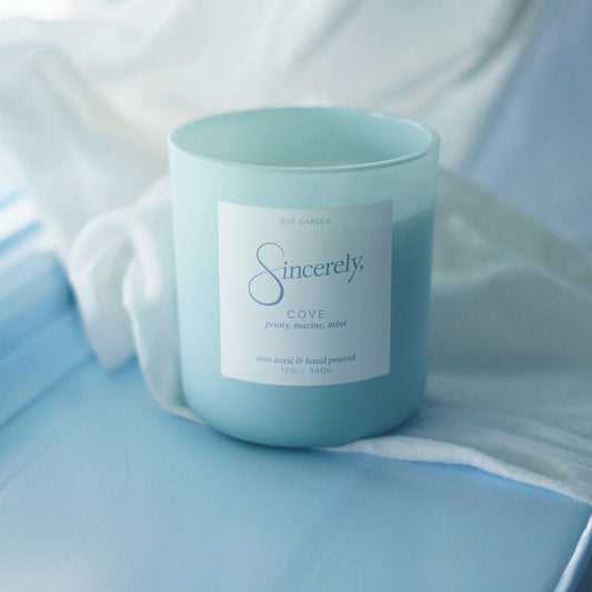 Light blue candle with a label on a light blue fabric background