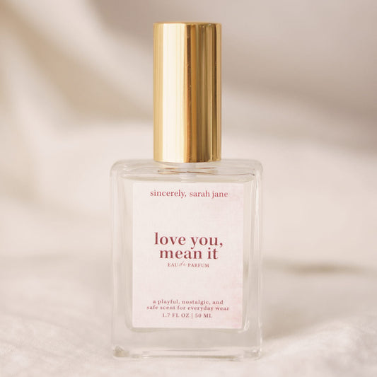 Perfume bottle with gold cap and white label on a beige background