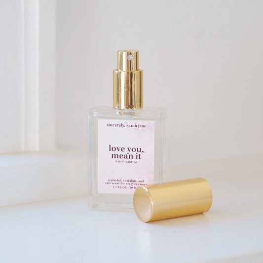 Perfume bottle with gold cap and white label on a light surface