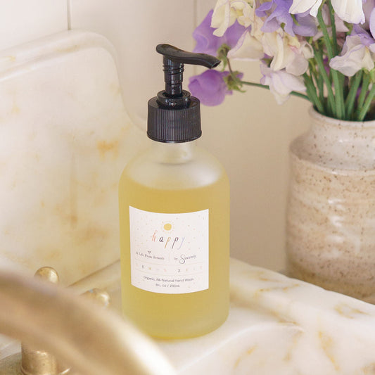 Bottle of liquid soap on a bathroom counter with flowers in the background