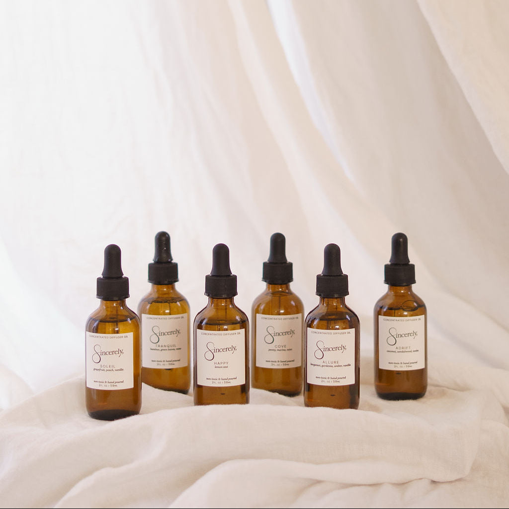 Set of six brown glass bottles with labels on a white fabric background