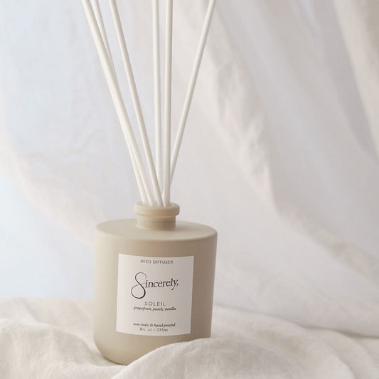 Reed diffuser with 'Sincerely' label on a soft fabric background