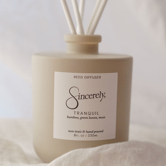 Reed diffuser labeled 'Sincerely' with 'Tranquil' fragrance on a soft white background