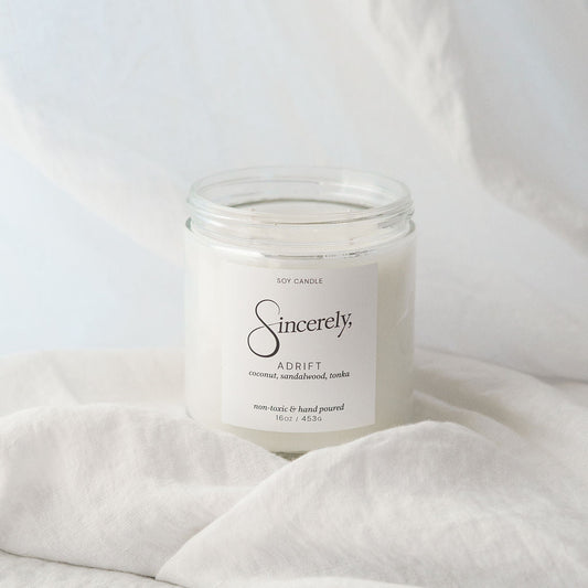 Candle labeled 'Sincerely' on a white fabric background