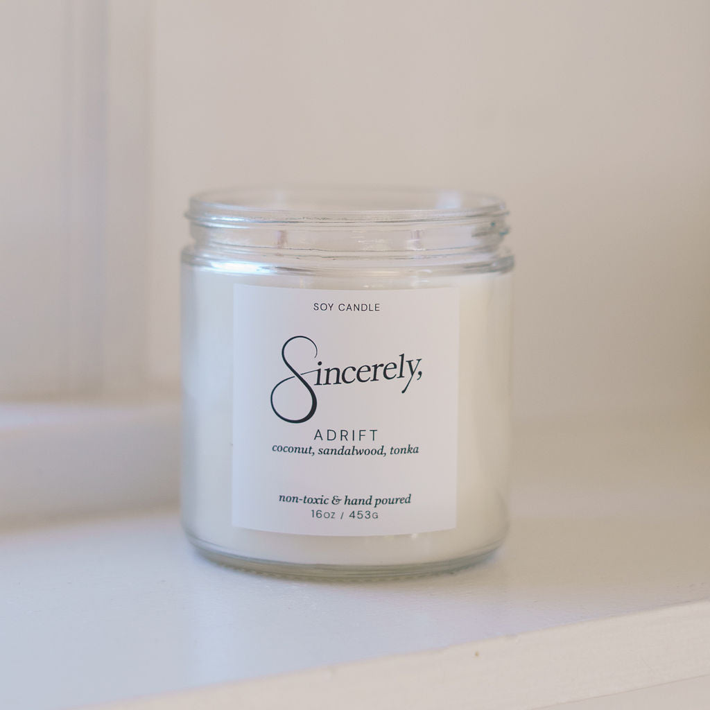 Candle jar labeled 'Sincerely' on a white surface with a white background