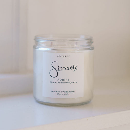 Candle jar labeled 'Sincerely' on a white surface with a white background