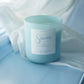 Light blue candle with a label on a light blue fabric background