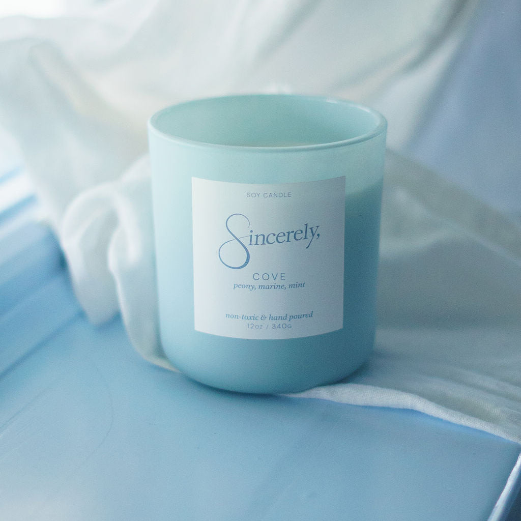 Light blue candle with a label on a light blue fabric background
