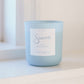 Light blue candle with a label on a white surface
