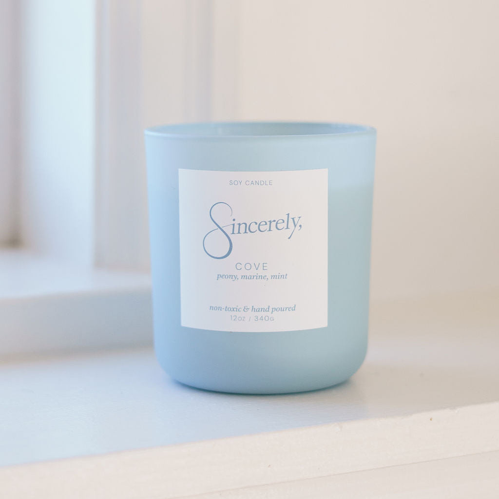 Light blue candle with a label on a white surface
