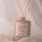Reed diffuser with wooden sticks in a beige container on a soft fabric background