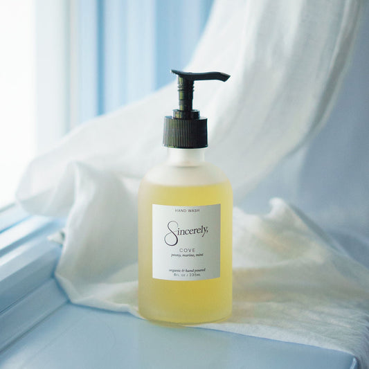Bottle of Sincerely Hand Wash product on a light blue surface with white fabric in the background