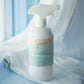 White cleaning spray bottle labeled 'Sincerely' on a light blue surface with white fabric.