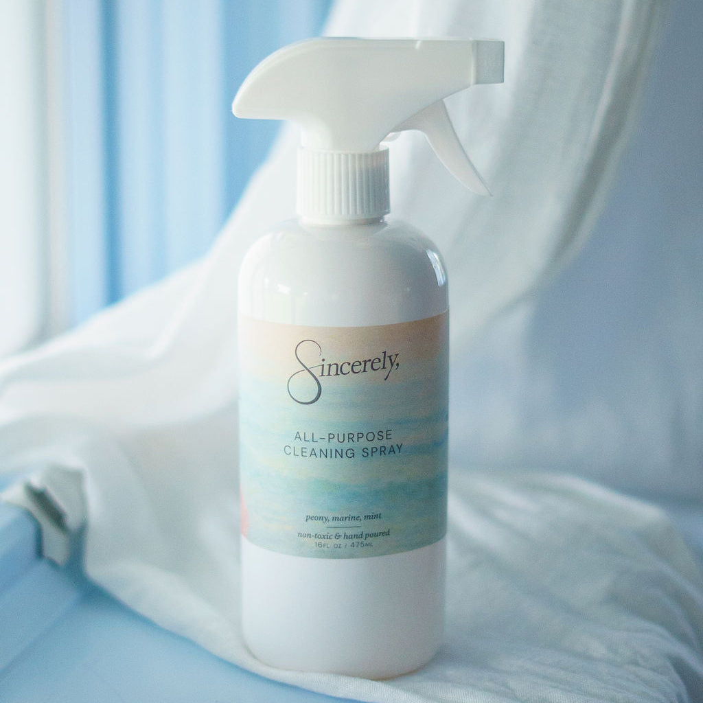 White cleaning spray bottle labeled 'Sincerely' on a light blue surface with white fabric.