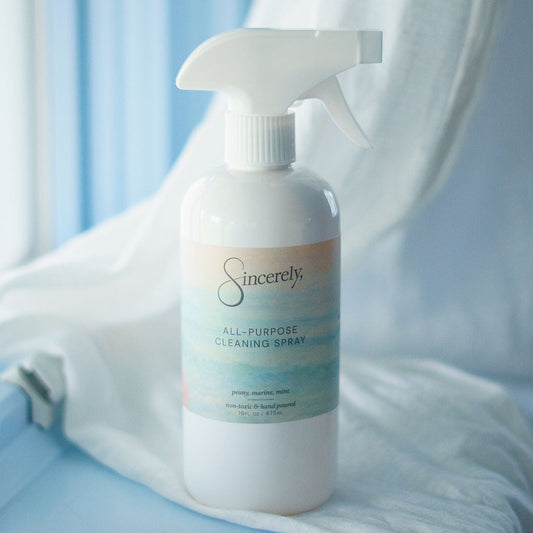 White cleaning spray bottle labeled 'Sincerely' on a light blue surface with white fabric.