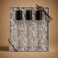 Three small glass bottles with black caps in a decorative box on a brown background