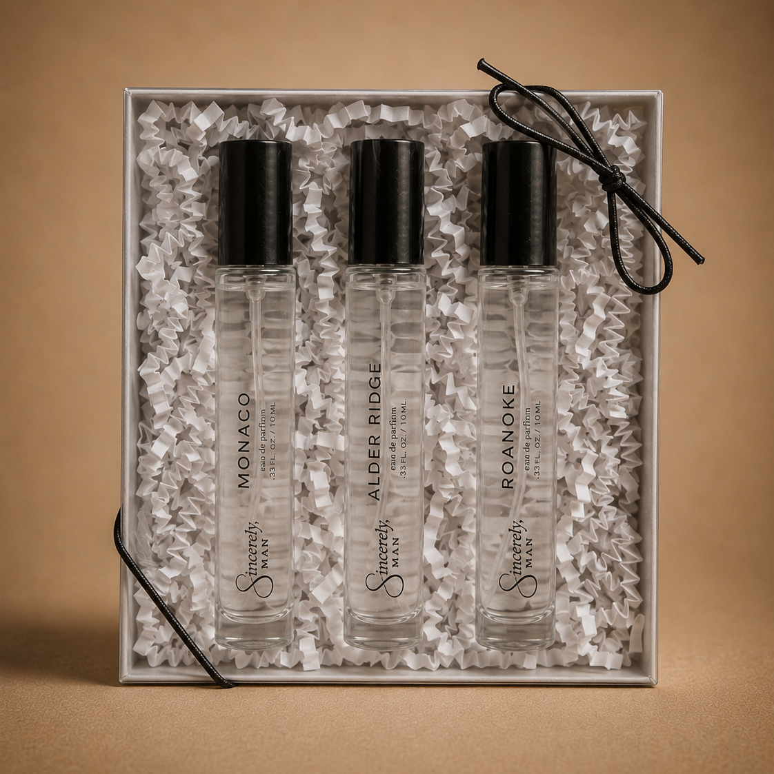 Three small glass bottles with black caps in a decorative box on a brown background