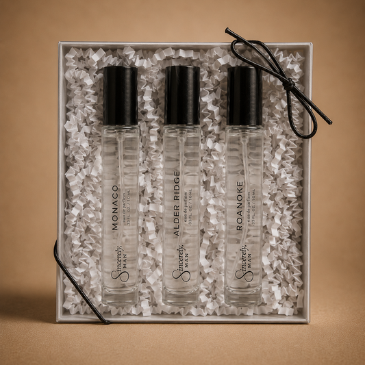 Three small glass bottles with black caps in a decorative box on a brown background