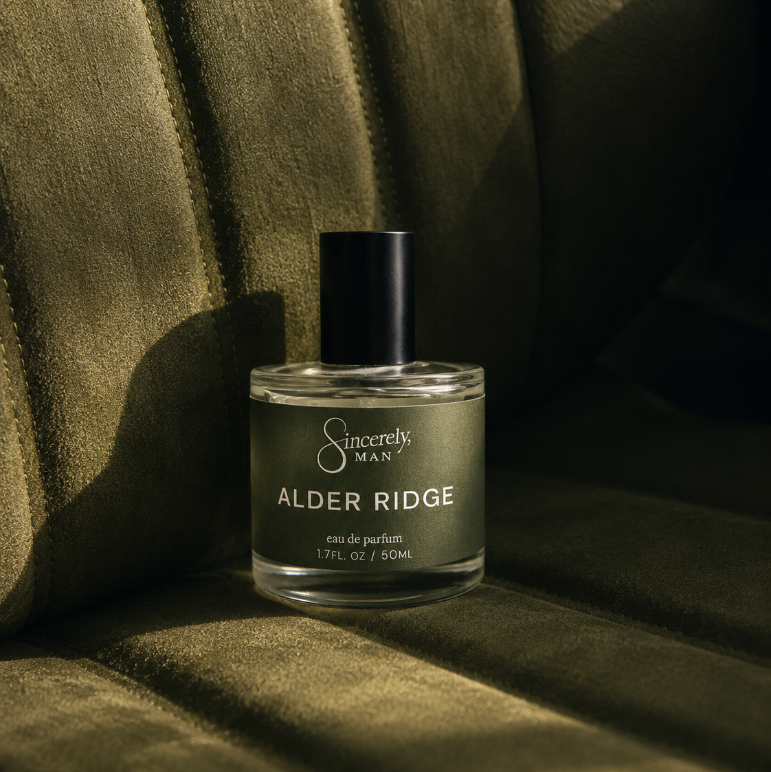 Scented bottle labeled 'Alder Ridge' by 'Sincerely Man' on a textured green surface.