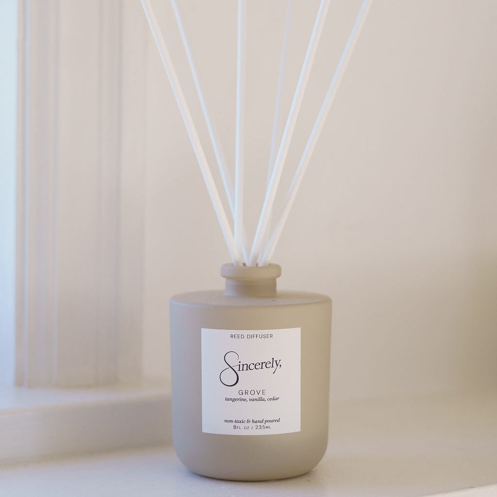 Beige diffuser bottle with white sticks on a light surface