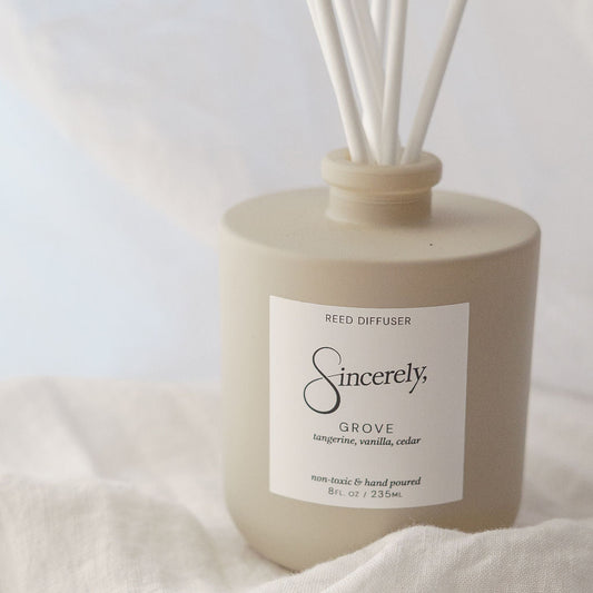 Reed diffuser labeled 'Sincerely' on a light fabric background