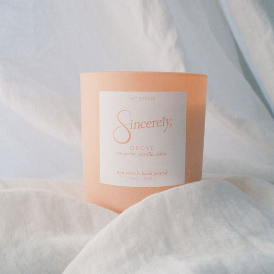Tangerine Candle with 'Sincerely' branding on a light fabric background