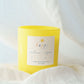 Yellow candle labeled 'happy' on a white fabric background