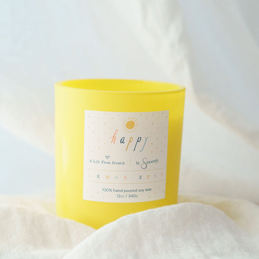 Yellow candle labeled 'happy' on a white fabric background