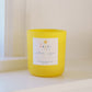 Yellow candle with a label on a white surface