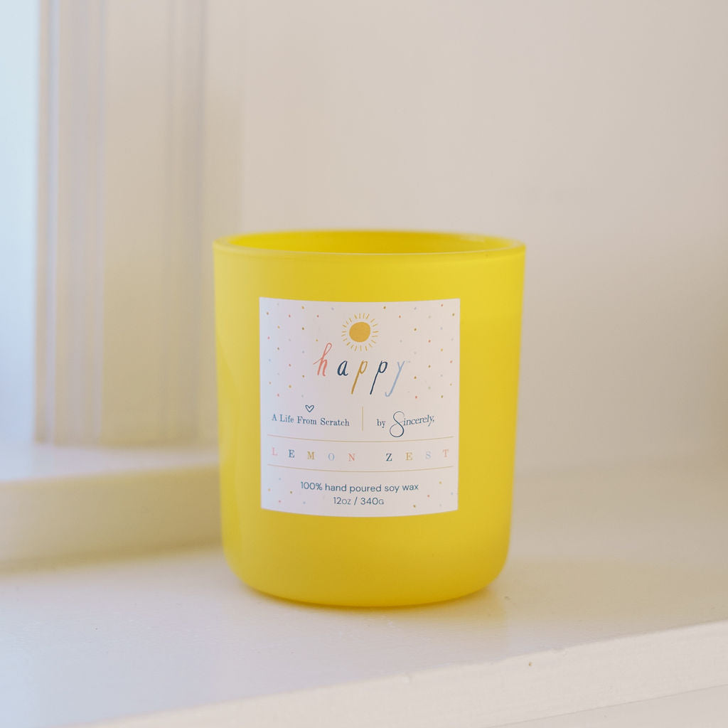 Yellow candle with a label on a white surface