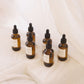 Set of glass dropper bottles with labels on a white fabric background