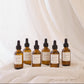 Set of six brown glass bottles with labels on a white fabric background