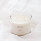 A 4-wick soy candle in a clear glass jar with white wax, labeled 'CHALET', set against a background of soft, draped white fabric.