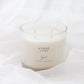 A 4-wick soy candle in a clear glass jar with creamy off-white wax, resting on draped white fabric. The label reads 'HYGGE'