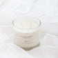 A 4-wick soy candle in a clear glass jar with white wax, labeled 'Autumn Leaves', styled on draped white fabric.