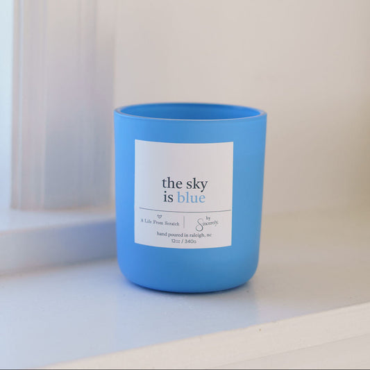 Blue candle with a label on a white surface