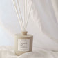 Reed diffuser with 'Sincerely' label on a soft fabric background