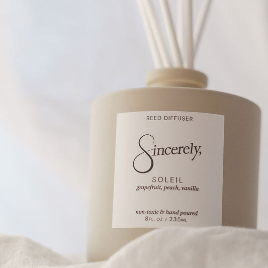 Reed diffuser labeled 'Sincerely' with 'Soleil' fragrance on a light background