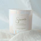 Candle labeled 'Sincerely' on a soft white fabric background