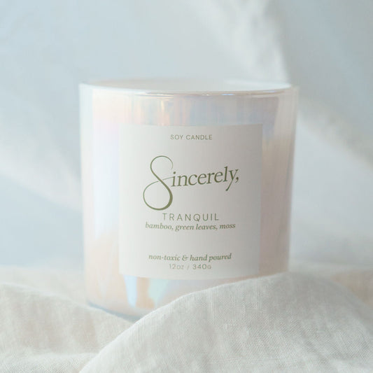 Candle labeled 'Sincerely' on a soft white fabric background