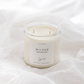 A small white soy candle in a clear glass jar with a white label reading 'WILDER' and 'Sincerely' branding, placed on soft white fabric.